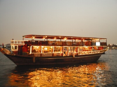 A beautifully decorated dhow sailing on the calm waters of Tudor Creek, Mombasa, with the setting sun in the background.