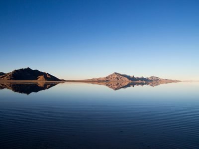 A lone acacia tree silhouetted against the setting sun over the vast expanse of Lake Turkana, with its distinctive turquoise waters.