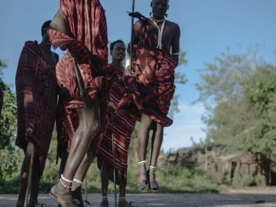 Maasai dancers in traditional attire performing a vibrant jumping dance at the Bomas of Kenya, with the audience watching in awe.