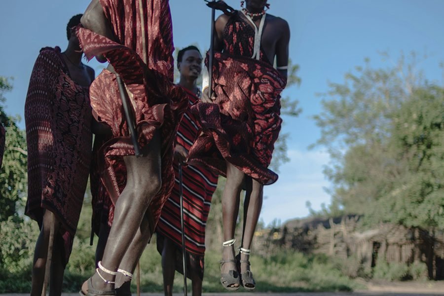 Maasai dancers in traditional attire performing a vibrant jumping dance at the Bomas of Kenya, with the audience watching in awe.